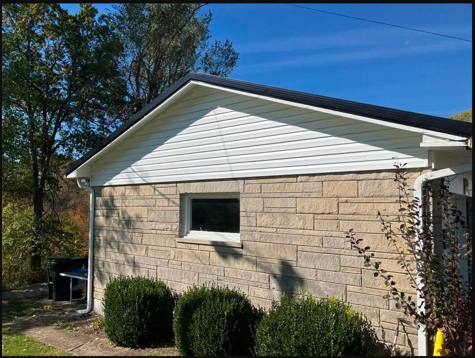 Finished white siding above an existing masonry wall