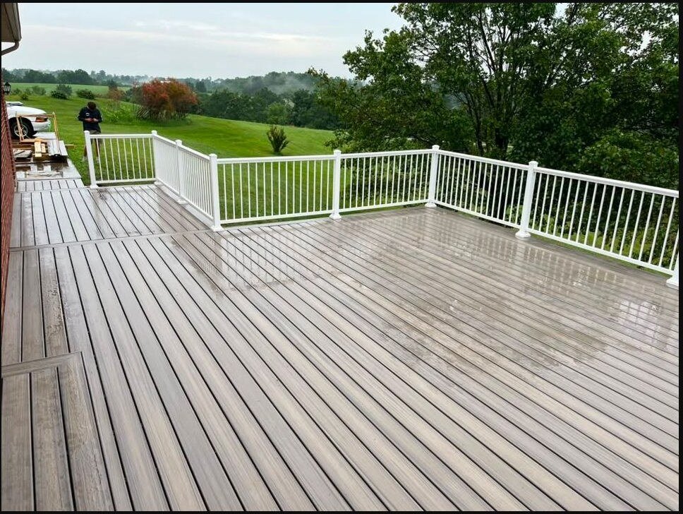 Large finished deck with white railing overlooking a rural landscape