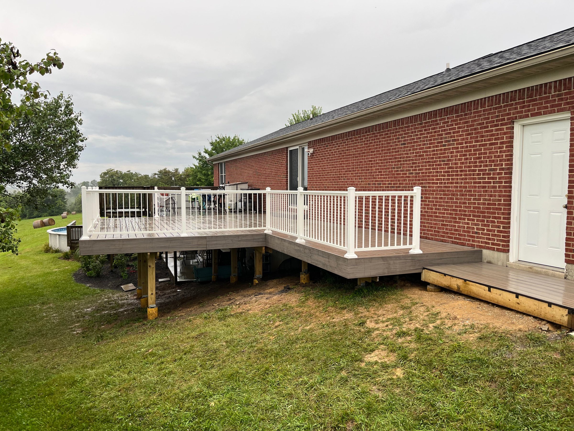 Completed composite deck with white railing beside a brick home