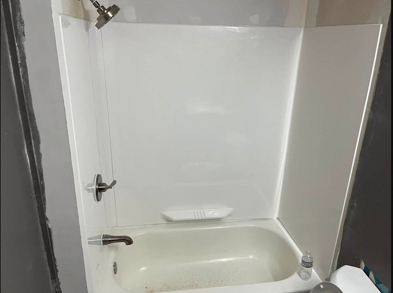 Installed white shower surround with new faucet, mixer and shower head