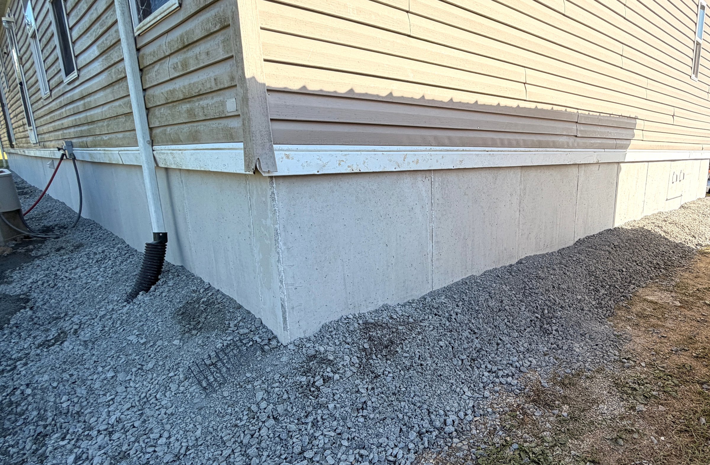 Finished DuraSkirt panels along a side elevation with gravel at the base