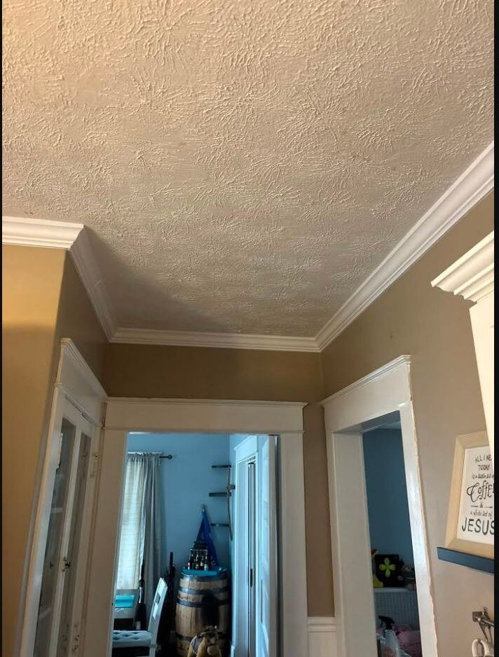 Finished crown molding and doorway trim in a residential hallway