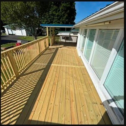 Long pressure-treated wood deck and railing alongside a home