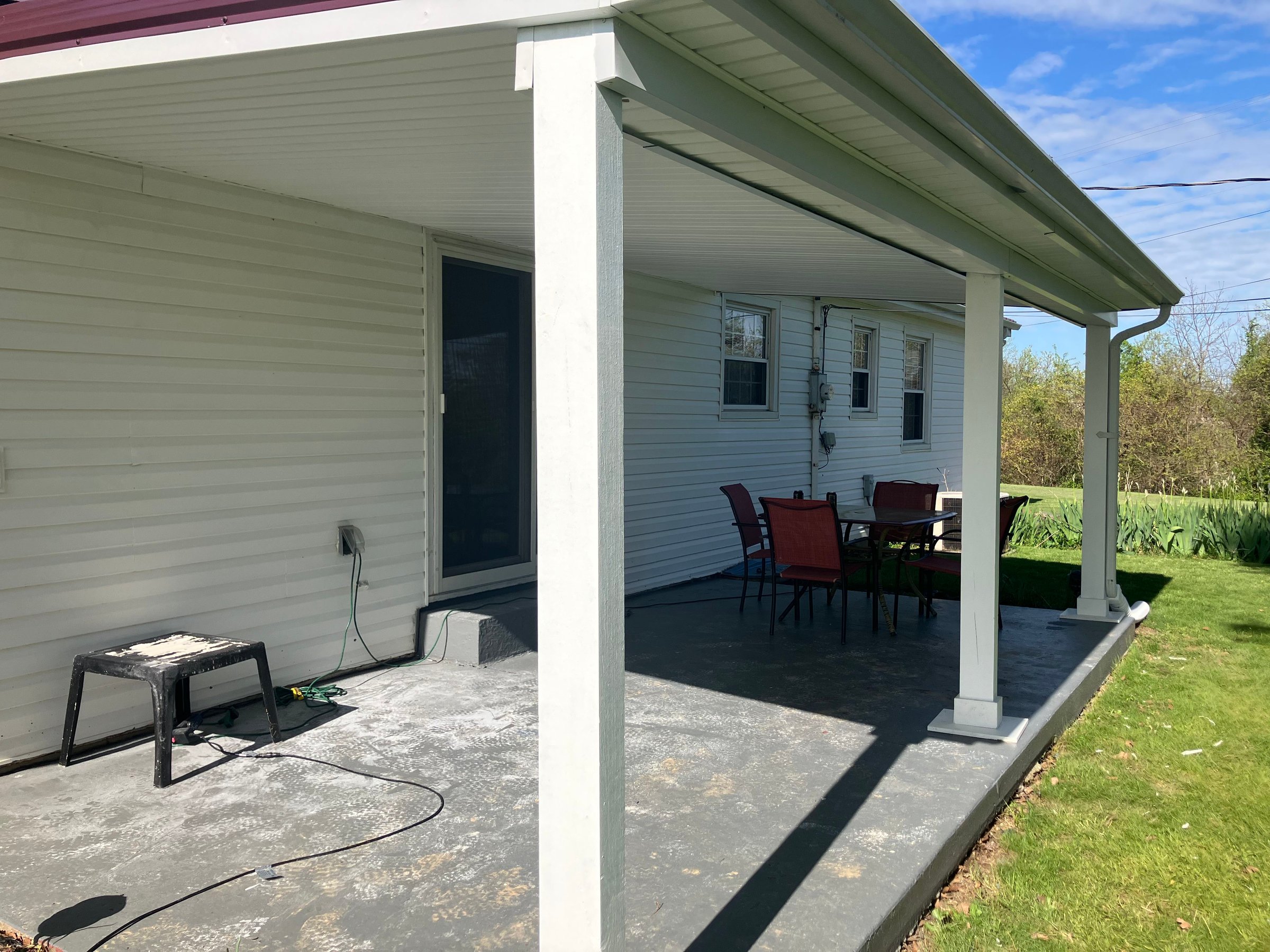 Completed covered patio with wrapped posts, soffit, fascia, and gutters