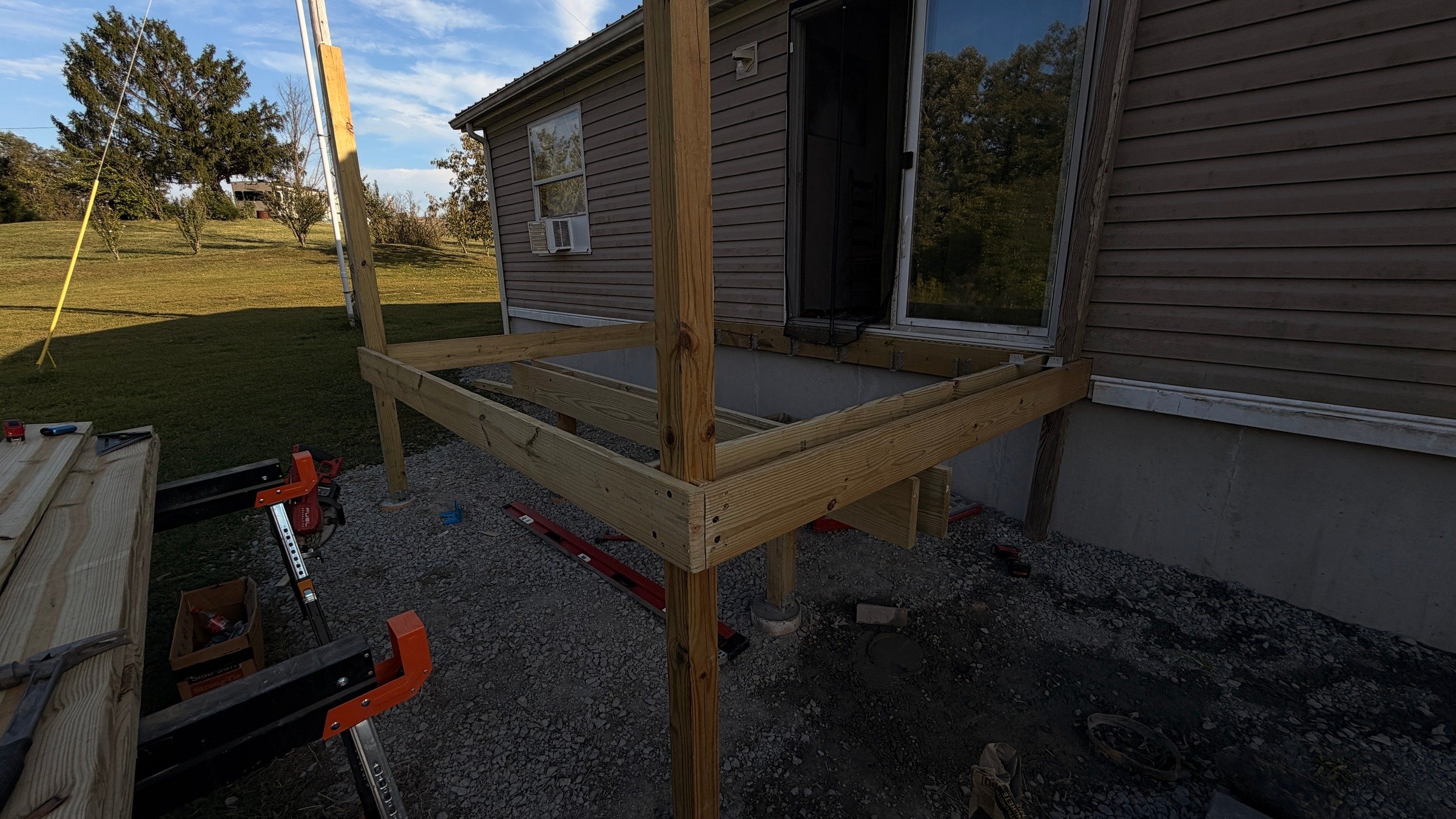 Timber entry-platform frame with open joists and posts beside a home