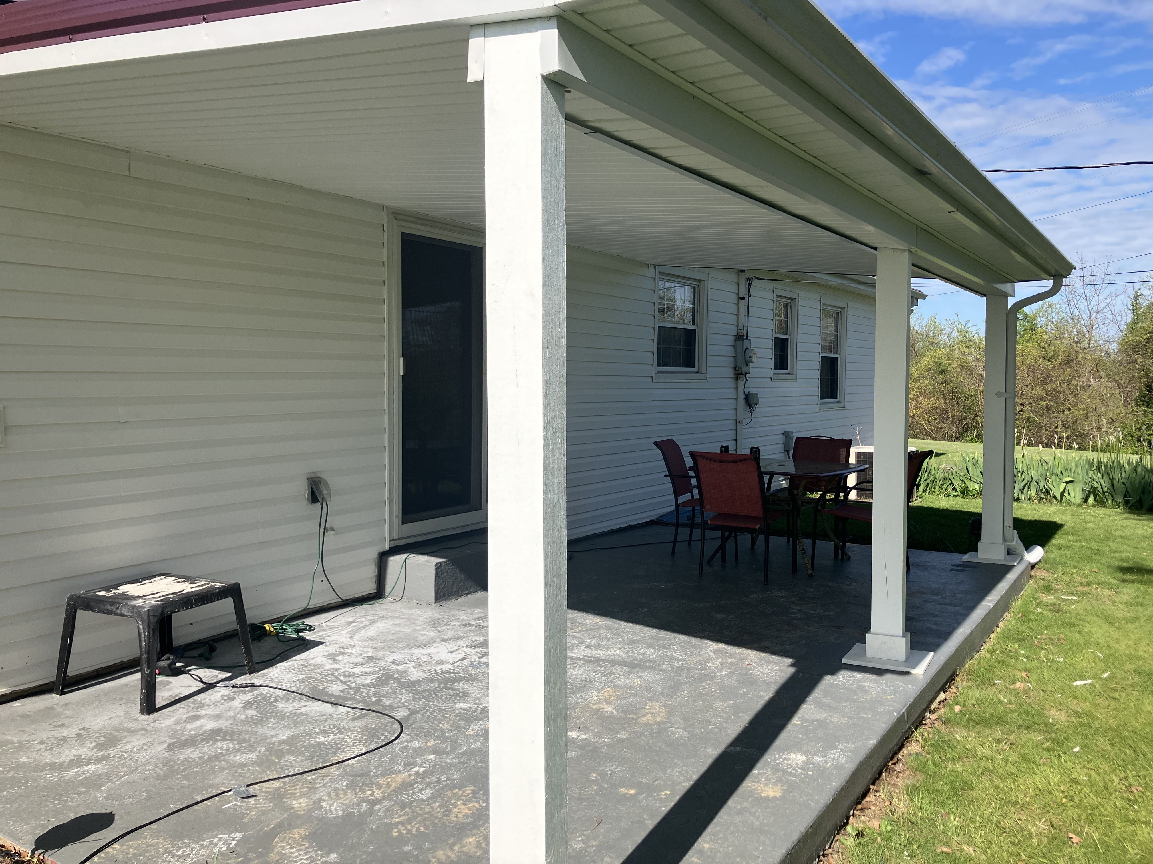 Completed covered patio with wrapped posts, soffit, fascia, and gutters